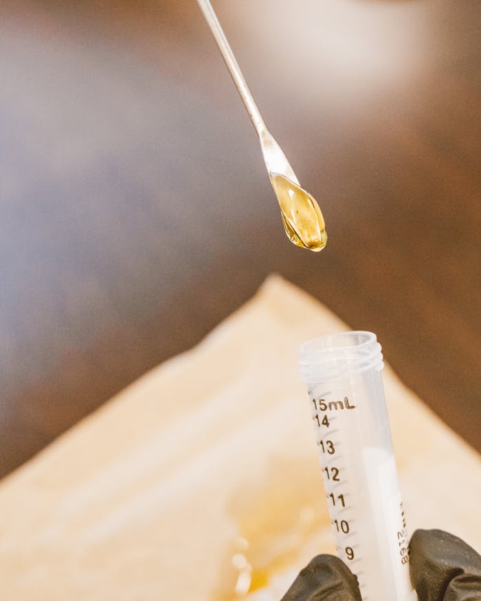 Close-up of a scientist pipetting a yellow liquid into a vial during laboratory research.